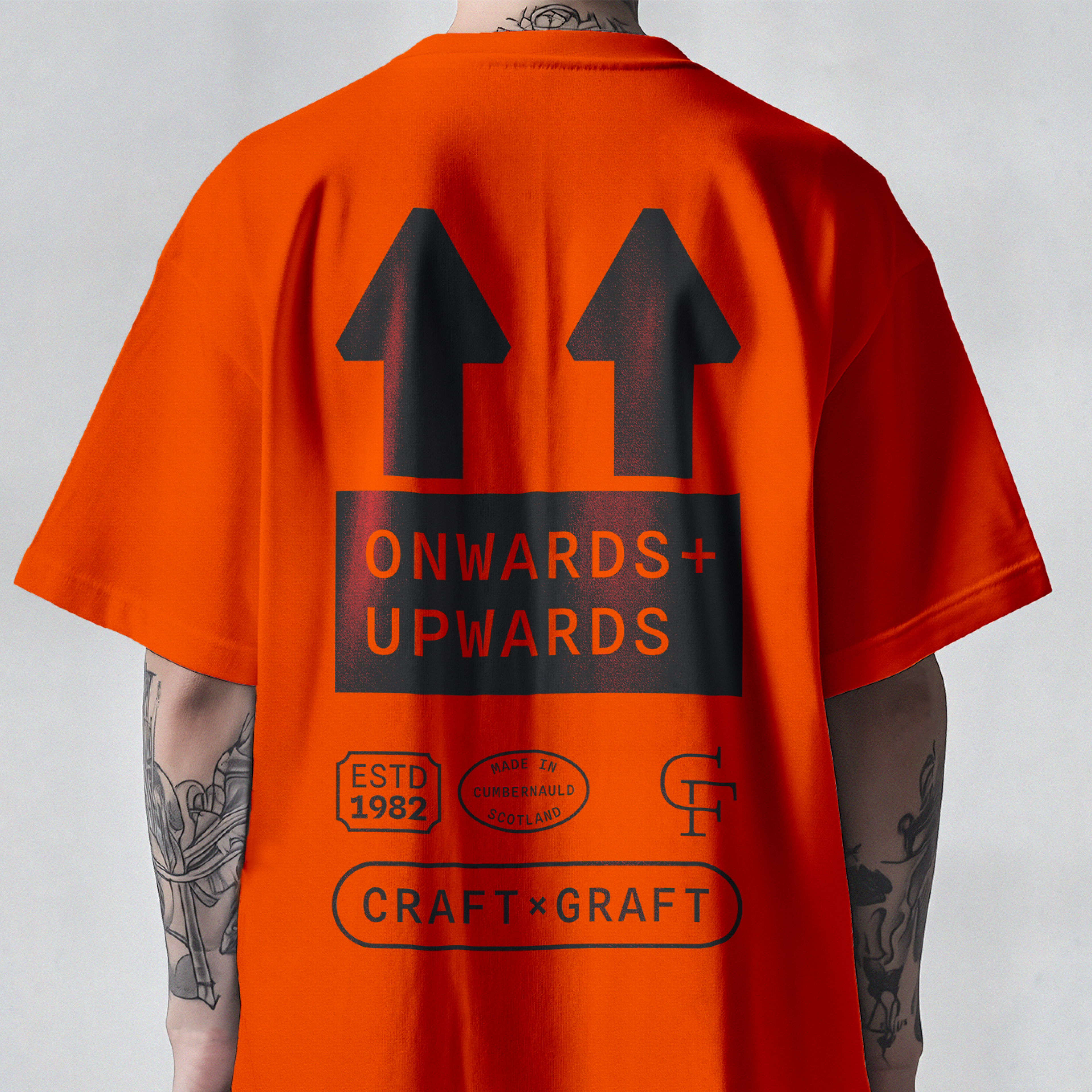 The back design of an orange Calfurn branded t-shirt, displaying various micrographics at a larger size, with emphasis on a large 'Onwards + Upwards' graphic based on a 'This way up' graphic