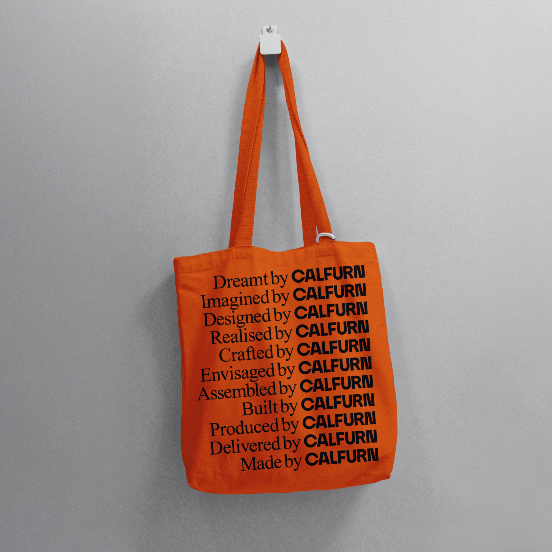 Orange Calfurn tote bag printed with the phrases "Dreamt by Calfurn" through to "Made by Calfurn", celebrating the brand's end-to-end craftsmanship.