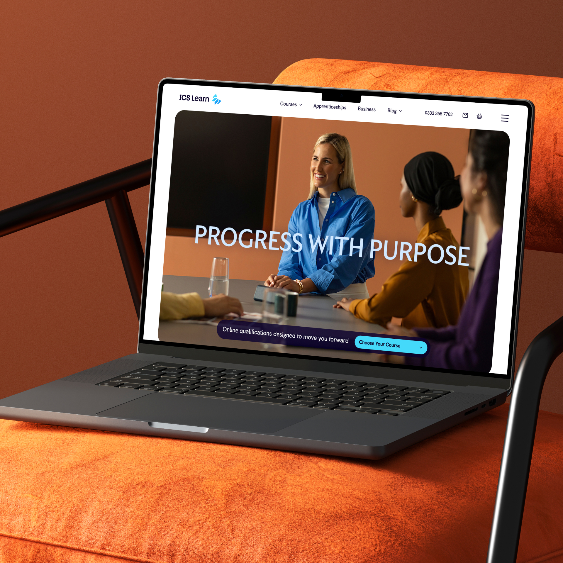 A laptop sitting on a stylist arm chair, with the ICS Learn homepage on the screen