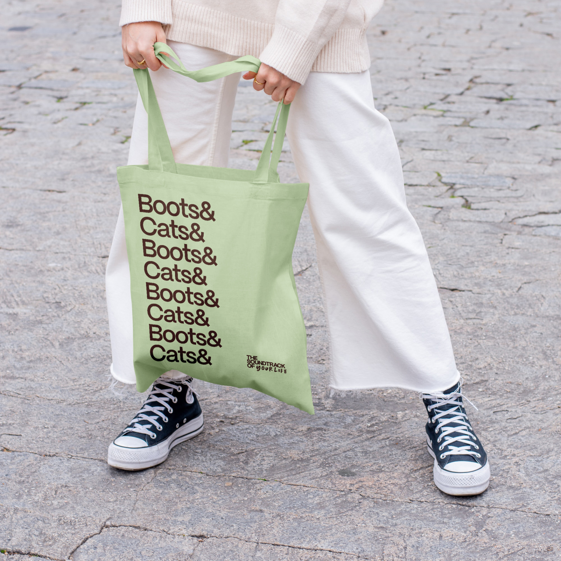 A tote bag with a typographic design repeating 'Boots & Cats'