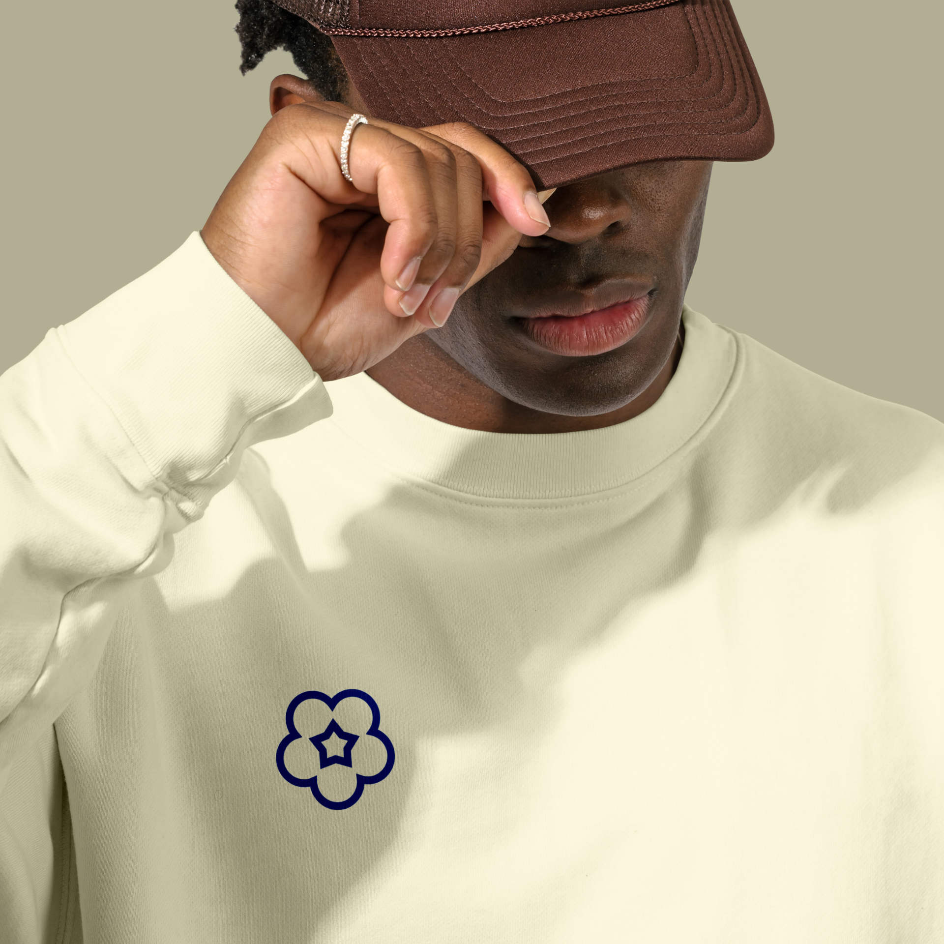 A man wearing a cream coloured Naru branded sweatshirt, with the logo on the chest area