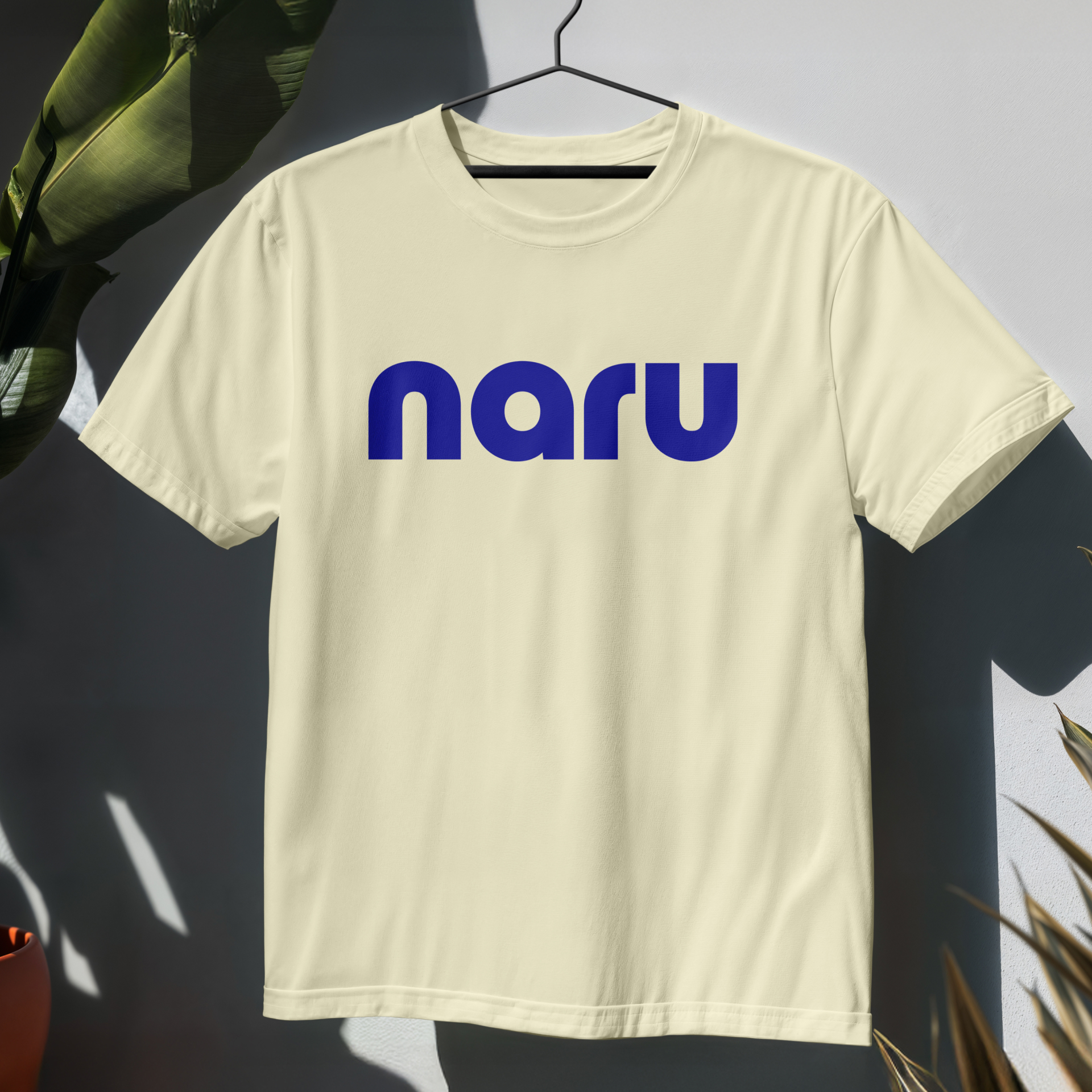 A Naru branded t-shirt, with a blue logo printed on a light cream coloured fabric
